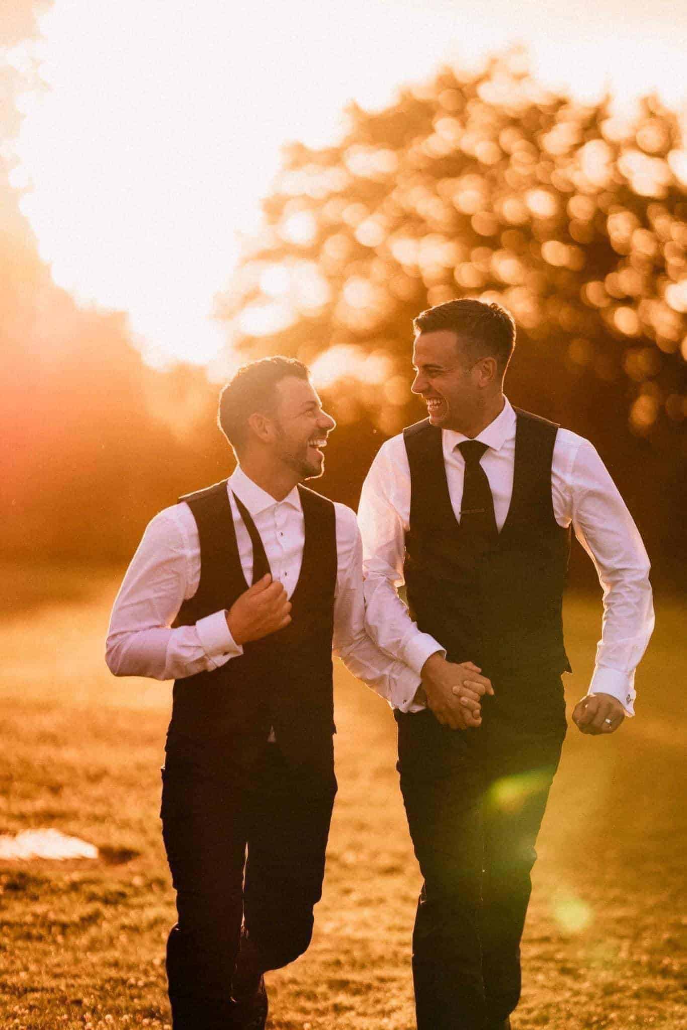 Same sex wedding couple having a great time running at sunset together laughing and joking naturally at their wedding at stubton hall