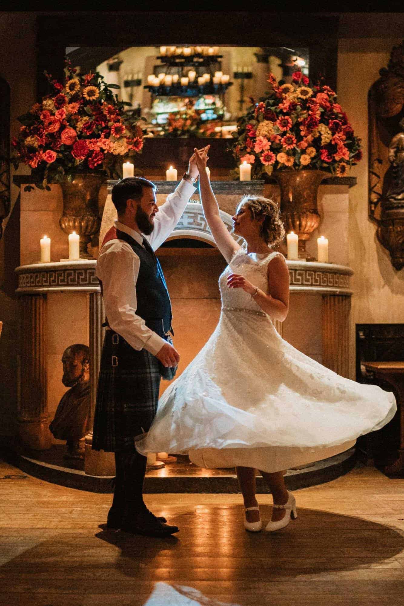 Groom spinning bride around in candlelight at a scottish wedding